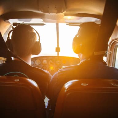 pilot and copilot in a cockpit during a sunset